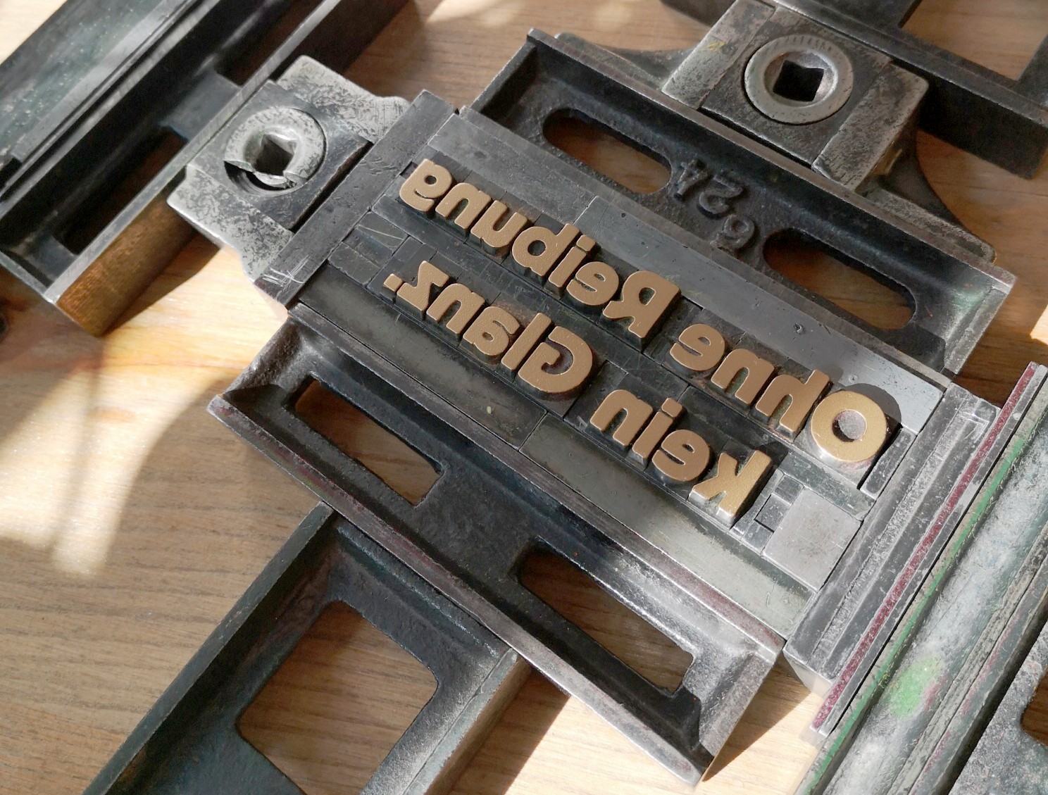 Metallische Drucklettern in einer Satzschiene zeigen die Wörter "eudgog anto" und "cap non" für Druckerei oder Schriftsatz.